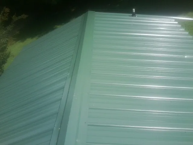New green metal panels meeting at the ridge of a roof — Flat Roof Repair work by our crew in Irvine